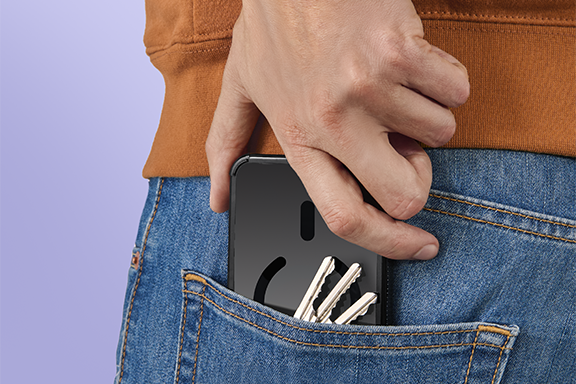 A person wearing jeans and a jumper takes a mobile phone with an Extreme Protect case out of their back pocket; the background is purple