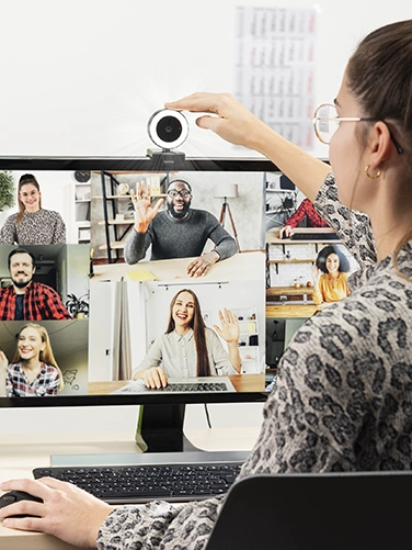 Woman adjusts the Hama webcam with ring light "C-800 Pro" on her monitor while talking to colleagues in a video call