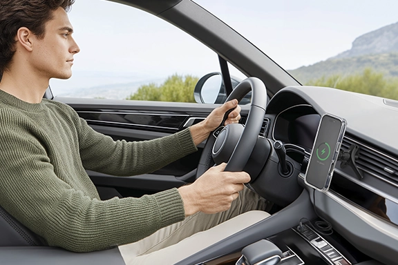 Smartphone is charged wirelessly in the car via Qi2 charger on the dashboard.
