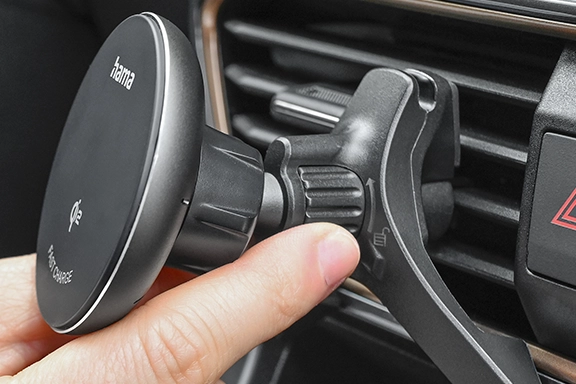 Man attaches magnetic smartphone holder to the air vent of a car.