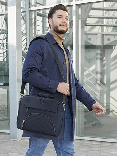 Businessman carries the Hama "Premium Lightweight" laptop bag over his shoulder on the way to the next meeting