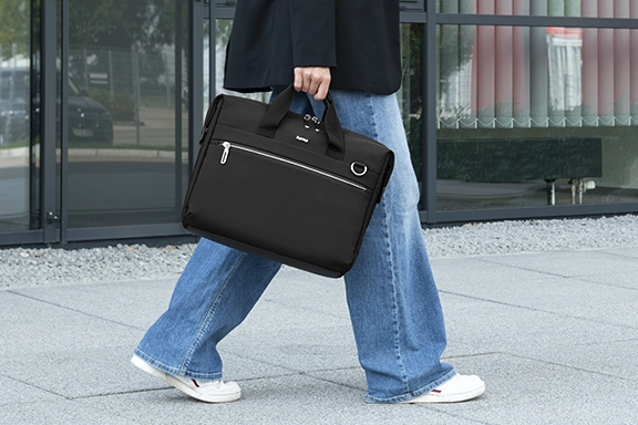 Close-up of a person using the black ‘Ultimate’ laptop bag as a briefcase and carrying it by the handles