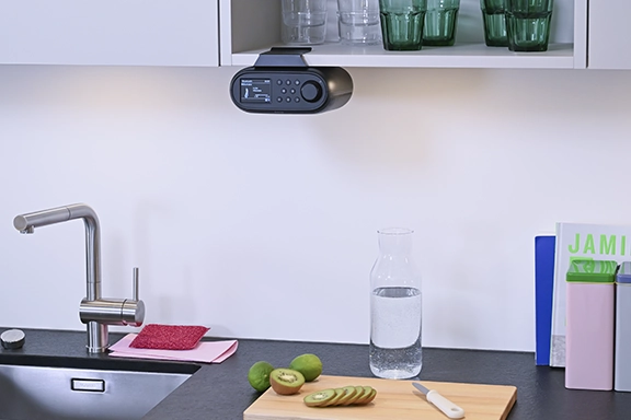 The digital and internet radio is mounted on the underside of a kitchen cupboard.