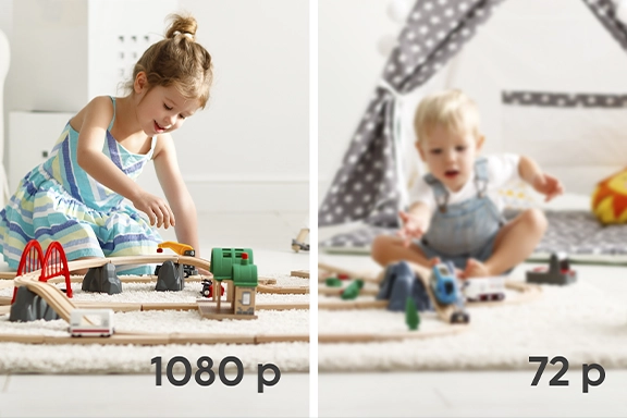 The picture is divided into two parts. On the left-hand side you can see a sharp image of a girl playing on the floor. On the right-hand side you can see, somewhat pixelated, the image of a small child sitting on the floor.